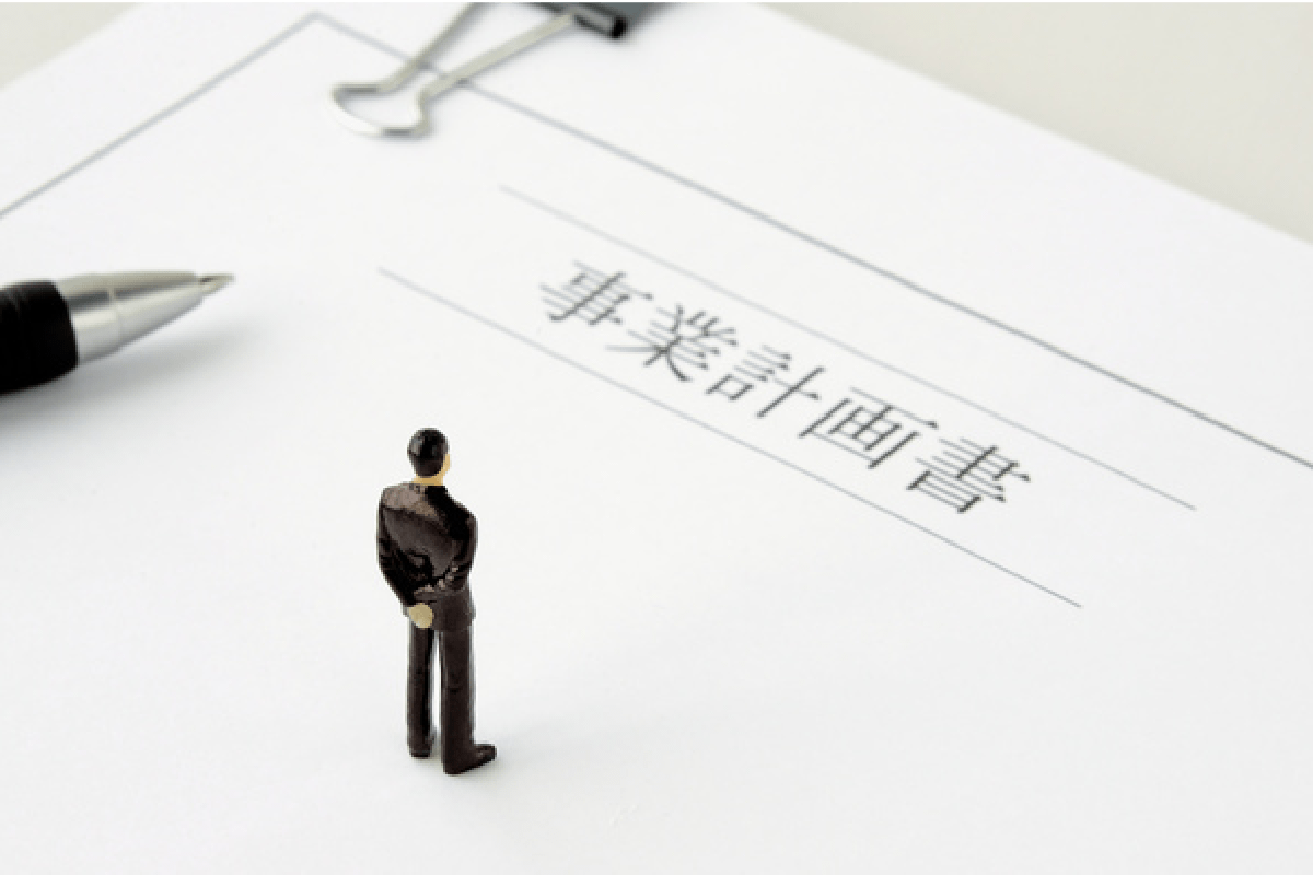 事業計画書と見つめる人形