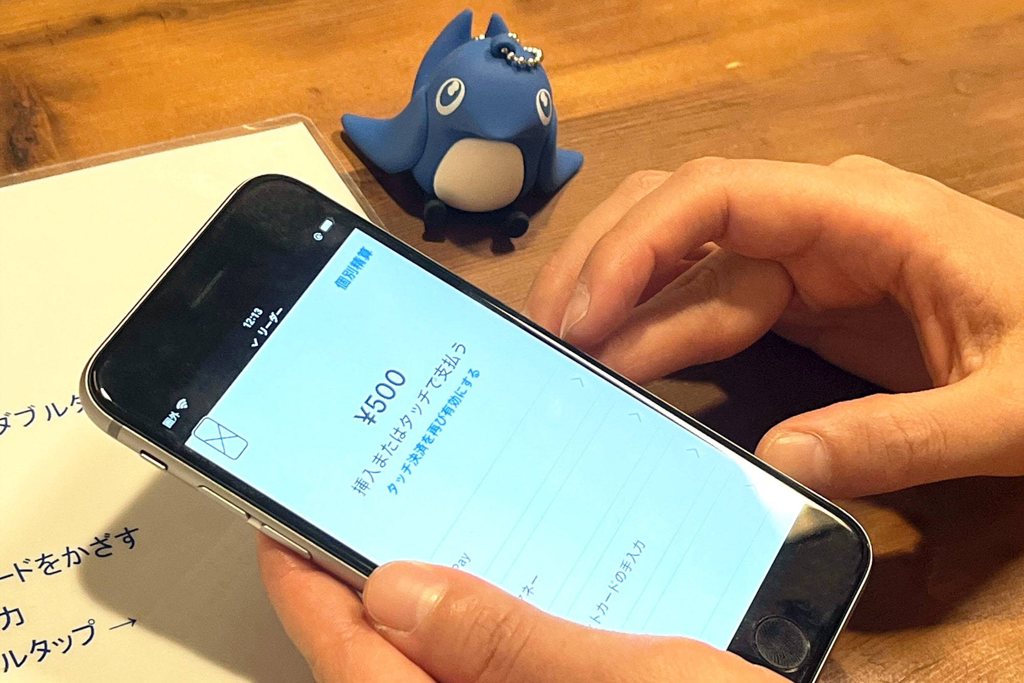 スマートフォンで経費精算をしている手元 傍らにfreee公式キャラクター「sweee」のマスコットが置かれている